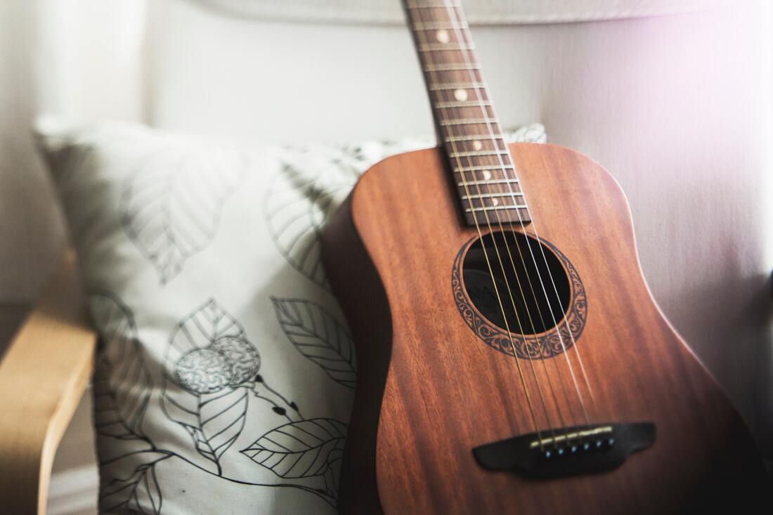 acoustic guitar resting on pillow